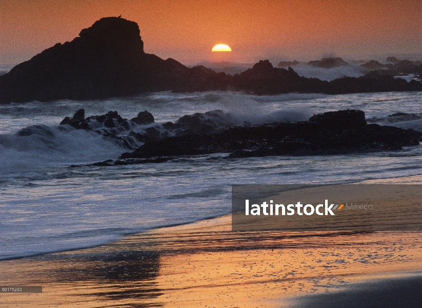 Estrellarse las olas en las rocas en la puesta del sol, punto de Piedras Blancas, California