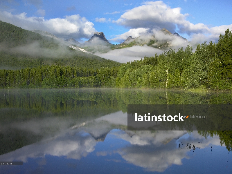 Fortaleza de montaña rodeada de nubes, reflejada en el lago, país de Kananaskis, Alberta, Canadá