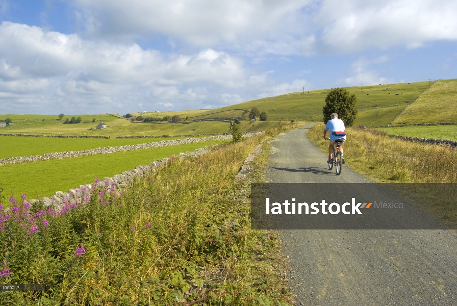 Ciclista en sendero a través de tierras de cultivo en el campo